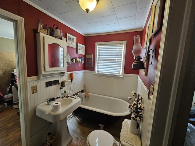 bathroom featuring hardwood / wood-style flooring, ornamental molding, toilet, and a bathing tub