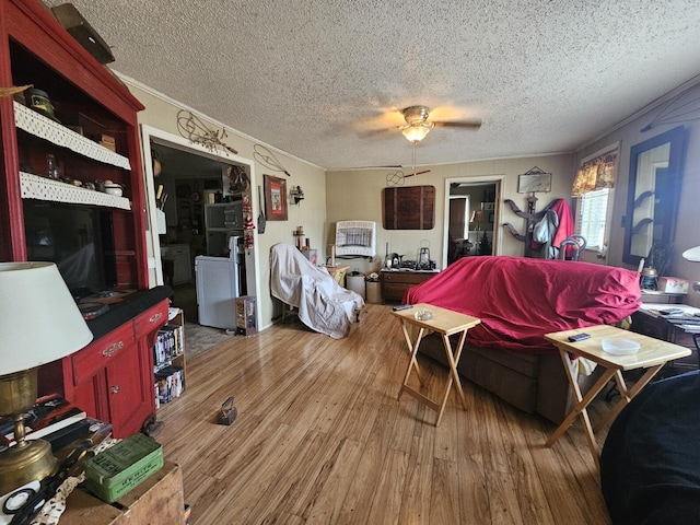 living room featuring hardwood / wood-style flooring, ceiling fan, crown molding, and a textured ceiling