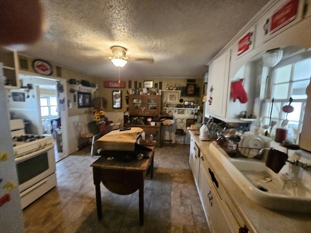 kitchen featuring sink, white cabinetry, a textured ceiling, dark hardwood / wood-style floors, and white gas range