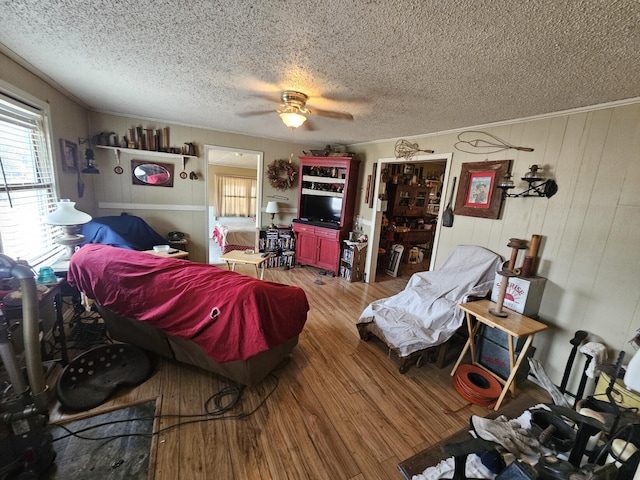 bedroom with hardwood / wood-style flooring, ceiling fan, wooden walls, and a textured ceiling