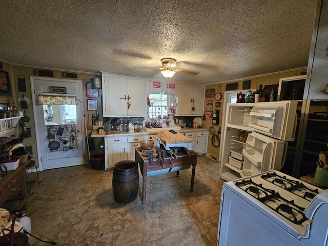 kitchen with ornamental molding, white cabinets, and white appliances