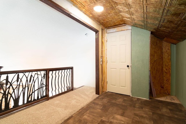 hall featuring lofted ceiling and dark carpet