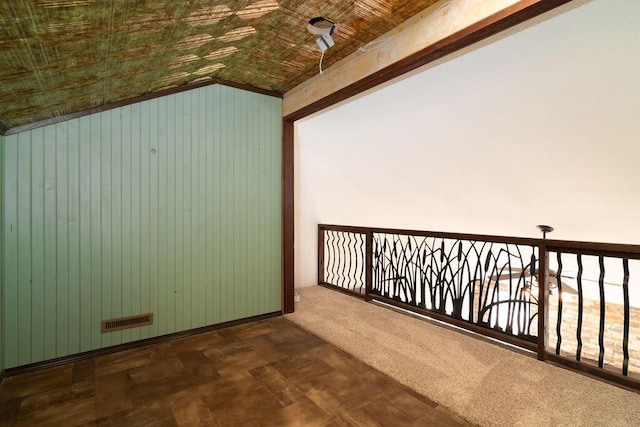 additional living space featuring lofted ceiling, wooden walls, wood ceiling, and dark carpet