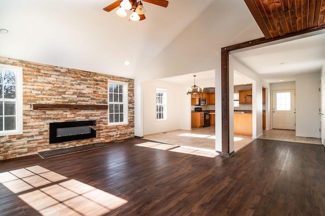 unfurnished living room featuring ceiling fan with notable chandelier, a fireplace, high vaulted ceiling, and light wood-type flooring