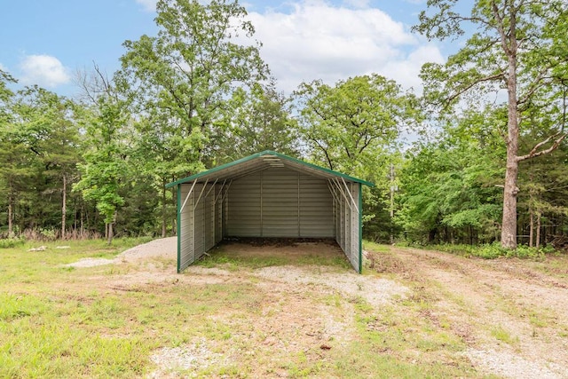 view of outbuilding with dirt driveway and a carport