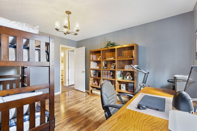 bedroom with a chandelier, baseboards, and light wood-style floors