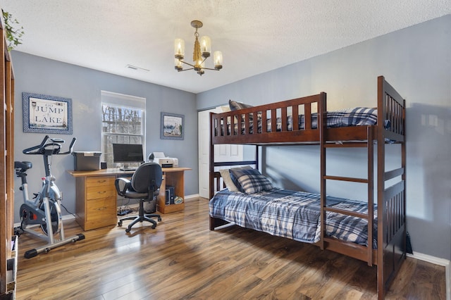 bedroom featuring baseboards, visible vents, wood finished floors, a textured ceiling, and a chandelier