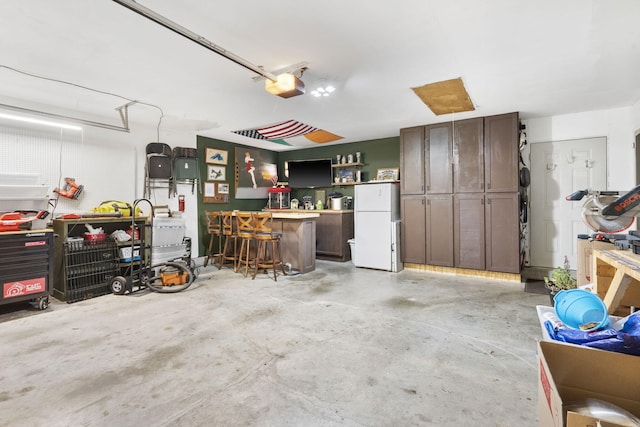 garage with a garage door opener and freestanding refrigerator