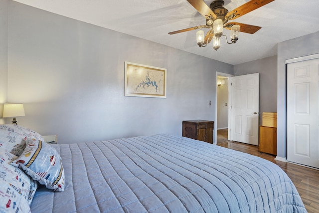 bedroom with dark wood-style flooring, a ceiling fan, and baseboards