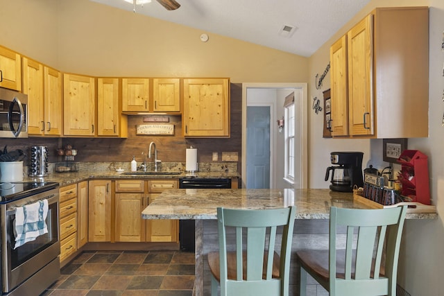 kitchen featuring light stone counters, stainless steel appliances, a breakfast bar, a peninsula, and a sink