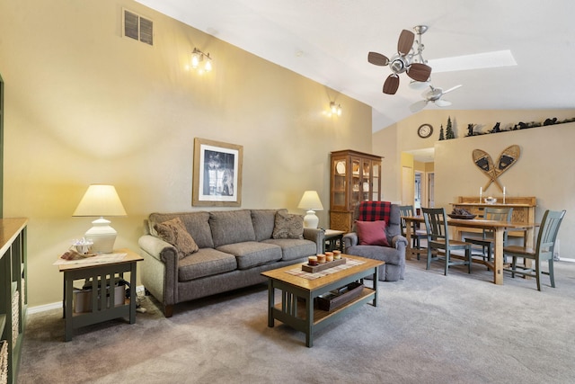 carpeted living area featuring ceiling fan, high vaulted ceiling, a skylight, and visible vents