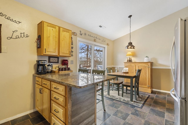 kitchen featuring visible vents, a kitchen breakfast bar, freestanding refrigerator, hanging light fixtures, and a peninsula