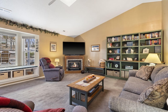 carpeted living area with vaulted ceiling with skylight, a glass covered fireplace, and visible vents