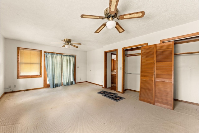 unfurnished bedroom with multiple closets, ceiling fan, light colored carpet, and a textured ceiling