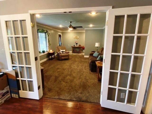 living room featuring dark wood-type flooring, ceiling fan, and crown molding