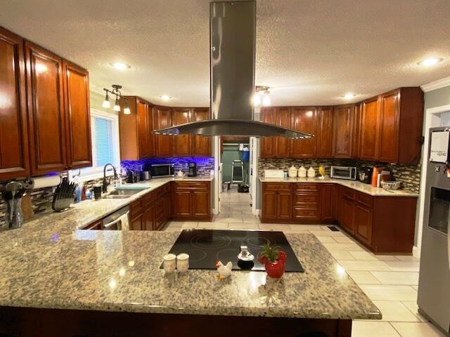 kitchen with sink, tasteful backsplash, appliances with stainless steel finishes, kitchen peninsula, and island exhaust hood