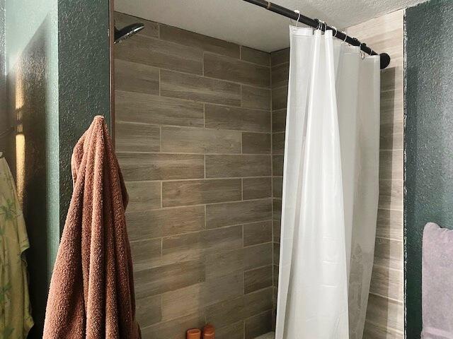 bathroom featuring a shower with curtain and a textured ceiling