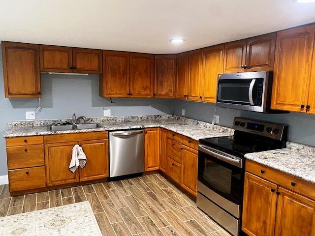 kitchen with light stone counters, appliances with stainless steel finishes, and sink