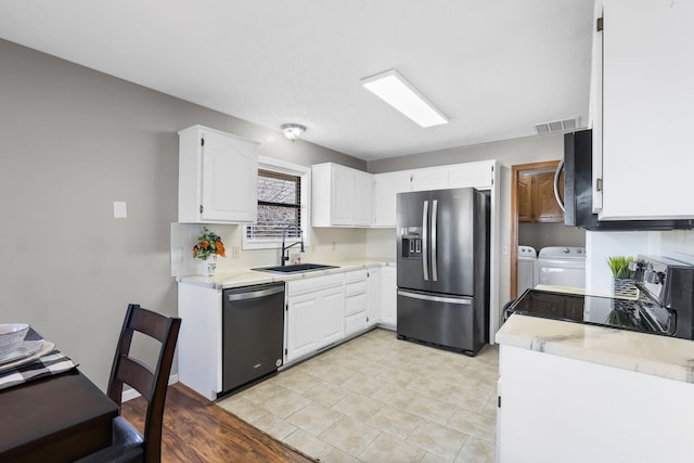 kitchen with white cabinetry, sink, washer and clothes dryer, and appliances with stainless steel finishes