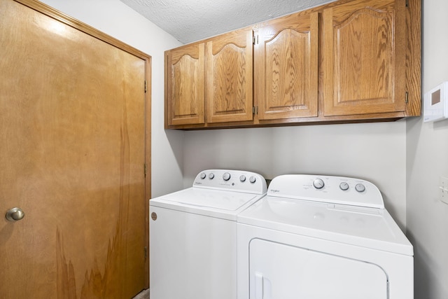 laundry area featuring cabinets, a textured ceiling, and washer and clothes dryer