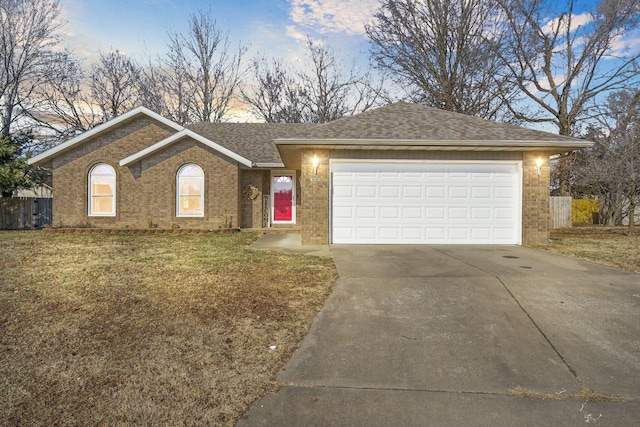 ranch-style house with a garage and a lawn