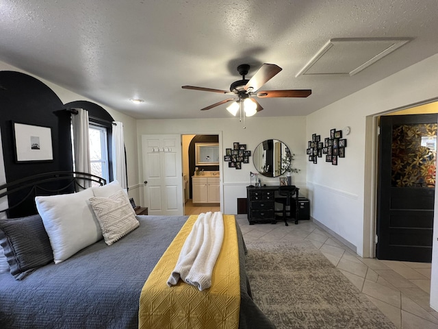 bedroom featuring attic access, light tile patterned floors, connected bathroom, and a textured ceiling