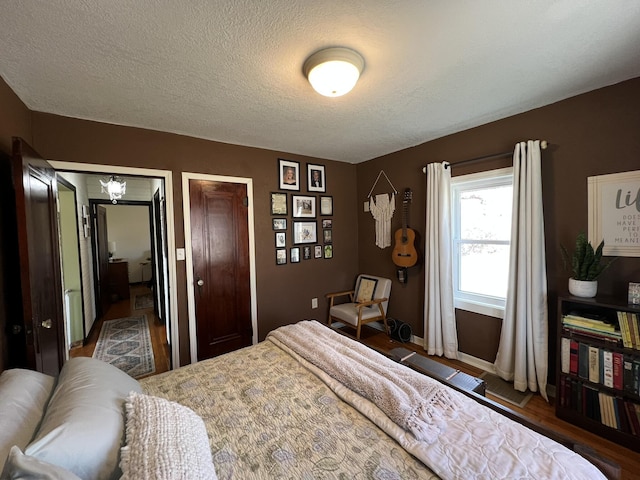 bedroom featuring multiple closets, baseboards, and a textured ceiling