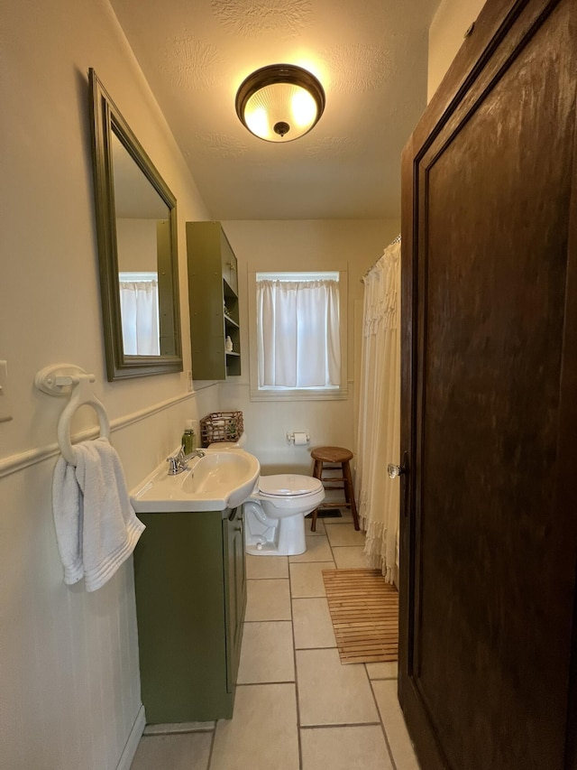 bathroom with tile patterned floors, a textured ceiling, toilet, and vanity