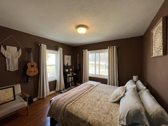 bedroom featuring baseboards, multiple windows, a textured ceiling, and dark wood-style flooring