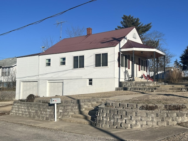 view of side of home with metal roof, an attached garage, and a chimney