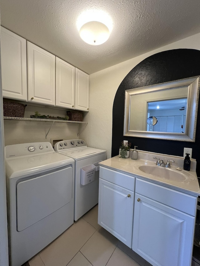 laundry area with washer and clothes dryer, cabinet space, a textured ceiling, and a sink