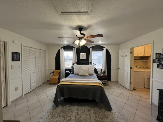 bedroom featuring washer and clothes dryer, light tile patterned floors, and arched walkways