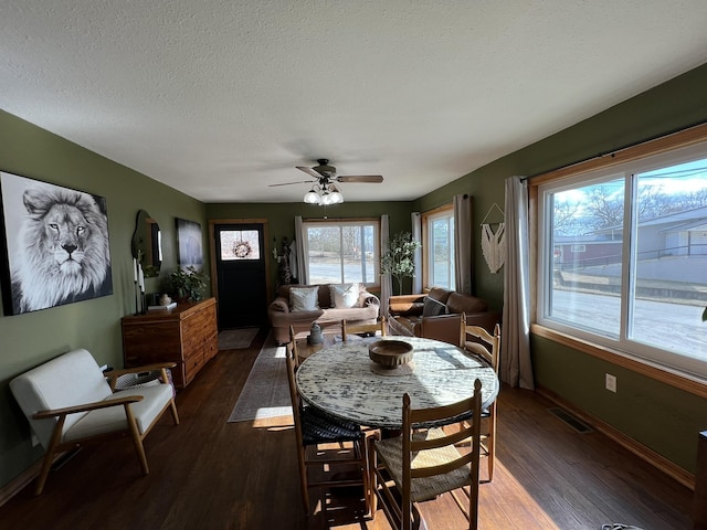 dining area featuring visible vents, a textured ceiling, dark wood-style floors, baseboards, and ceiling fan