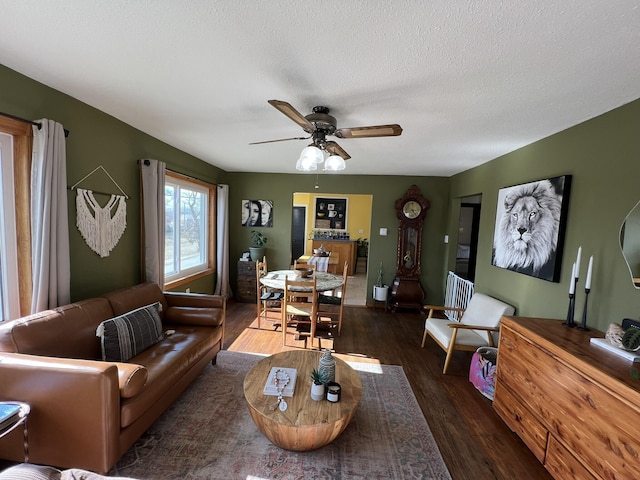 living area with ceiling fan, a textured ceiling, and wood finished floors