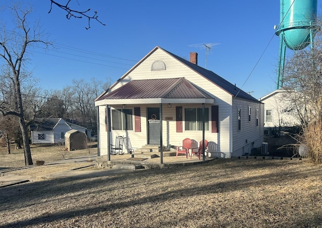 bungalow-style house with a chimney, central air condition unit, and metal roof