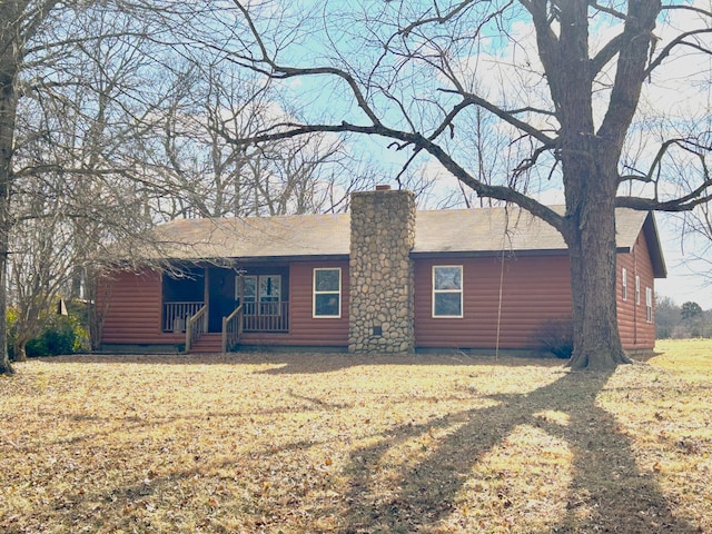 rear view of house featuring a porch and a lawn