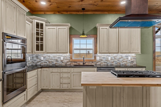 kitchen featuring butcher block counters, sink, hanging light fixtures, island exhaust hood, and stainless steel appliances