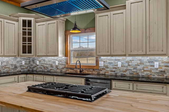 kitchen with butcher block counters, sink, stainless steel gas stovetop, cream cabinets, and exhaust hood