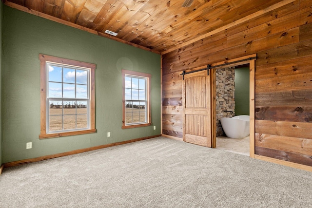 unfurnished bedroom with a barn door, light carpet, and wooden ceiling