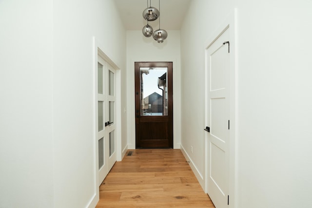 doorway to outside featuring a chandelier and light hardwood / wood-style floors