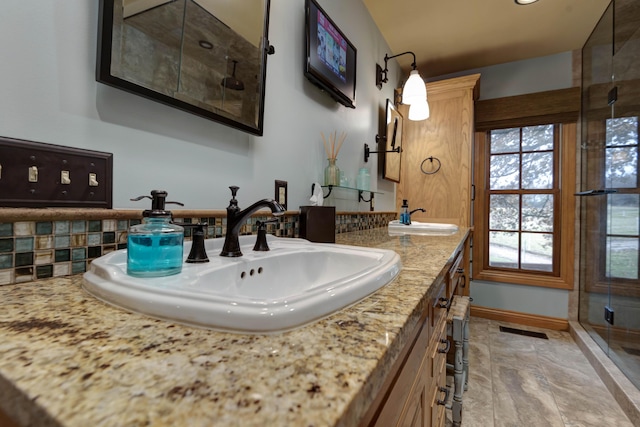 bathroom featuring a shower with door, vanity, a healthy amount of sunlight, and decorative backsplash