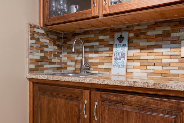 details featuring sink, backsplash, and light stone counters