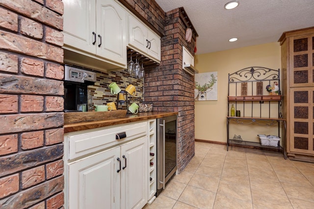 kitchen with white cabinetry, wine cooler, a textured ceiling, and light tile patterned flooring