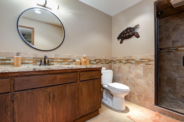 bathroom featuring a shower with shower door, tile walls, vanity, toilet, and tile patterned floors