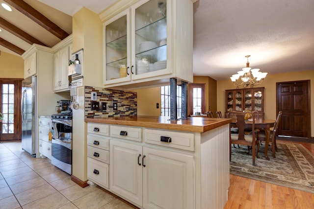 kitchen featuring an inviting chandelier, tasteful backsplash, lofted ceiling with beams, pendant lighting, and stainless steel appliances