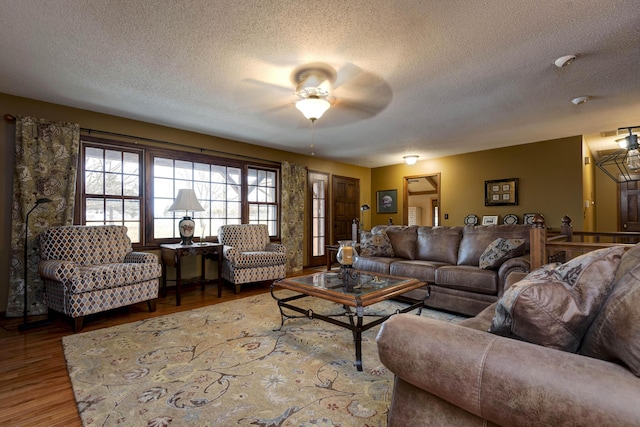 living room featuring hardwood / wood-style flooring, ceiling fan, and a textured ceiling