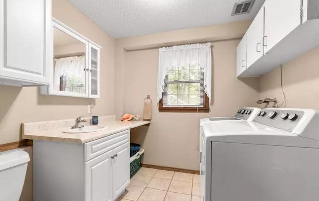 laundry room featuring light tile patterned flooring, separate washer and dryer, sink, and a textured ceiling