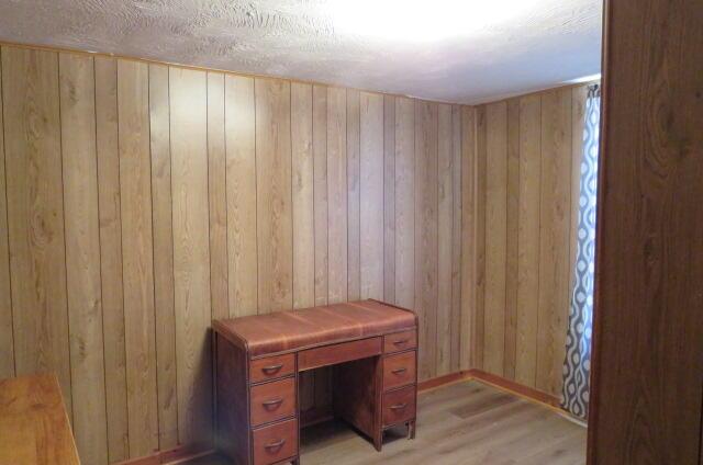 unfurnished office with light wood-type flooring and wood walls