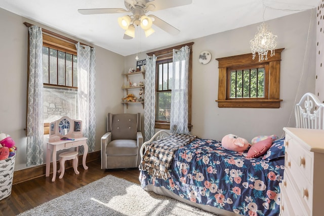 bedroom featuring ceiling fan with notable chandelier and dark hardwood / wood-style flooring