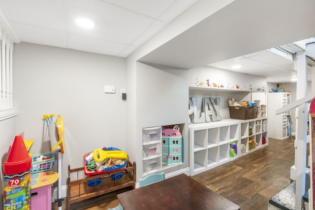 playroom featuring dark wood-type flooring and a paneled ceiling